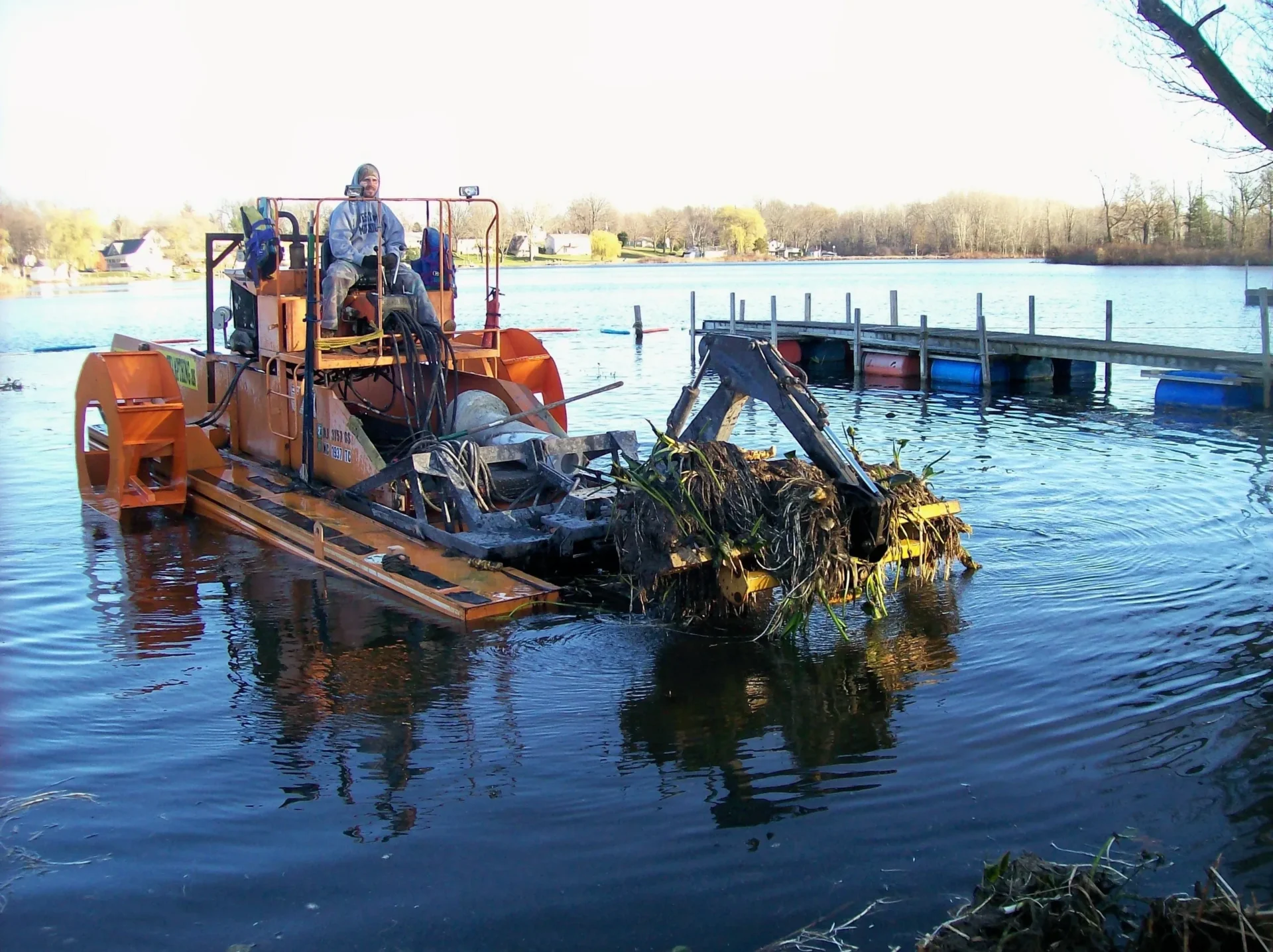 A man on an orange tractor in the water.