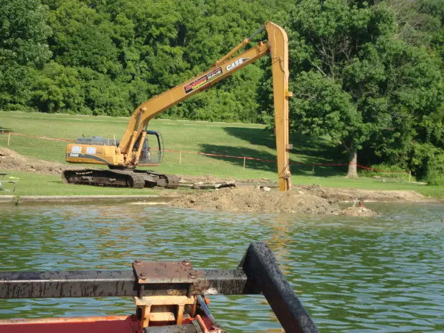 A large yellow excavator is in the water.