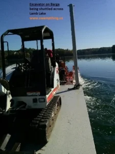 A boat with a tractor on it going down the water.