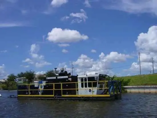 A large boat floating on the water near some trees.