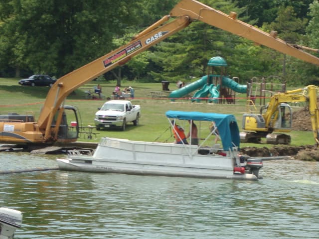 A boat is in the water near some construction equipment.