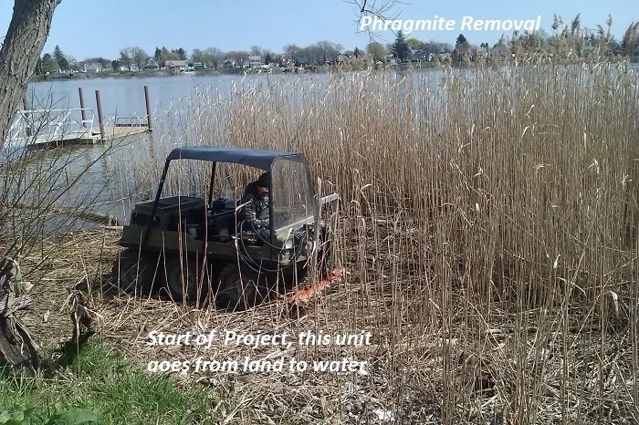 A black atv parked in the grass near some water.