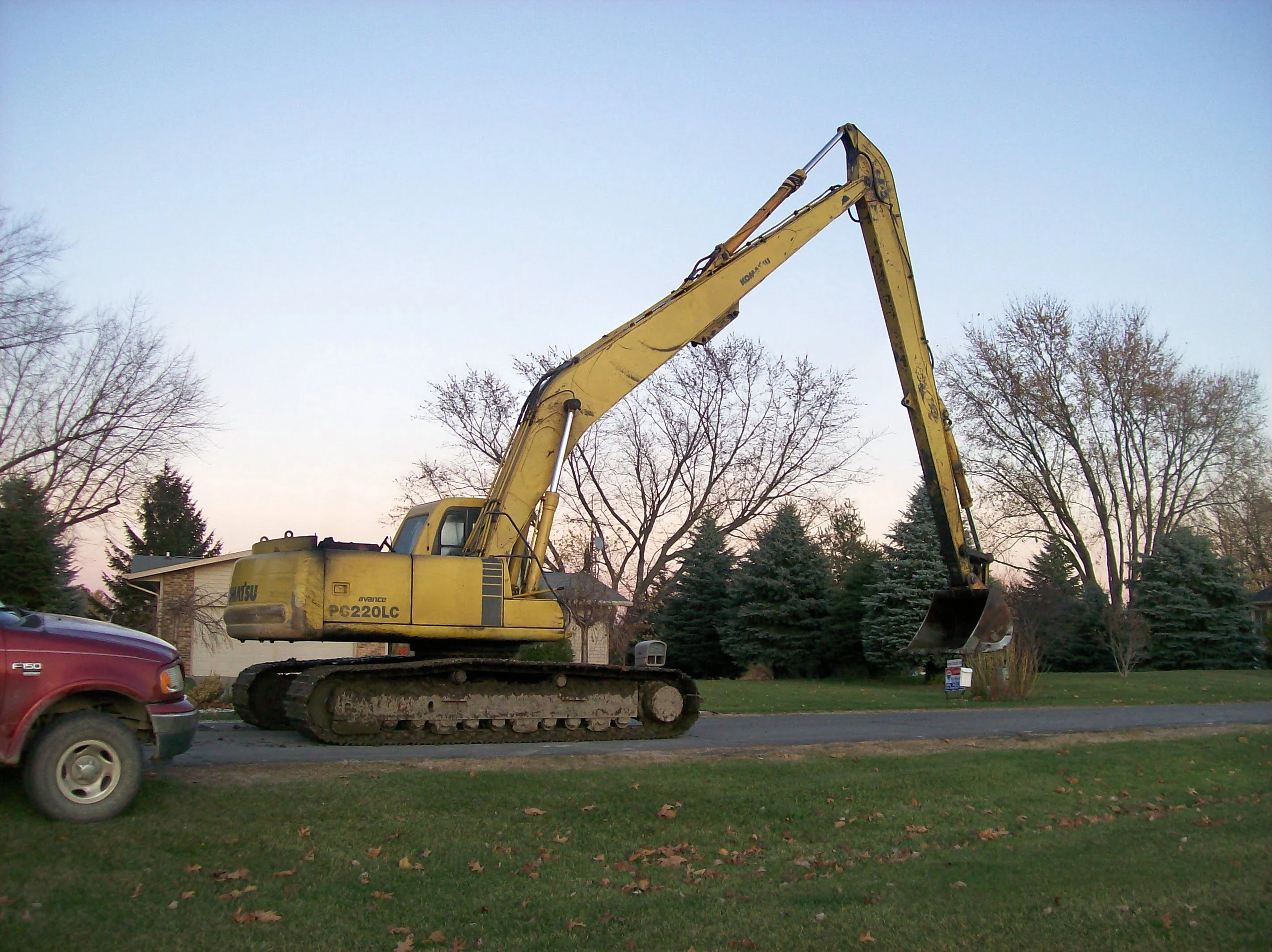 A yellow crane is on the ground near some trees.