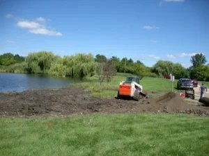 A truck is parked in the grass near some water.