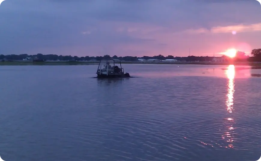 A boat is in the water at sunset.