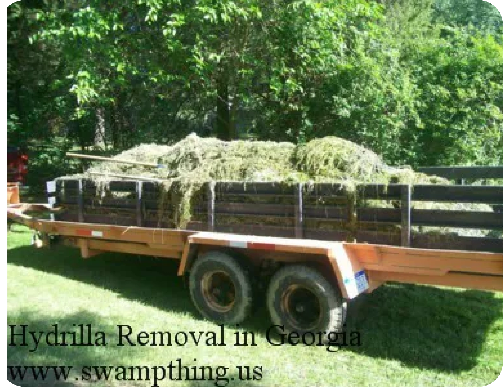 A large trailer with hay on it in the grass.