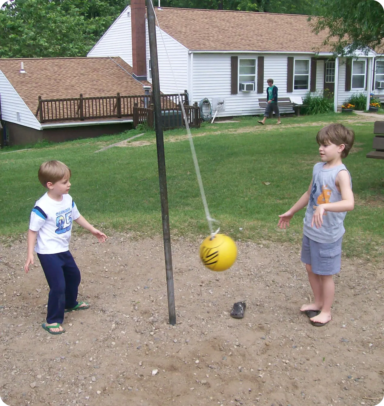 Two young boys playing with a ball on the ground.